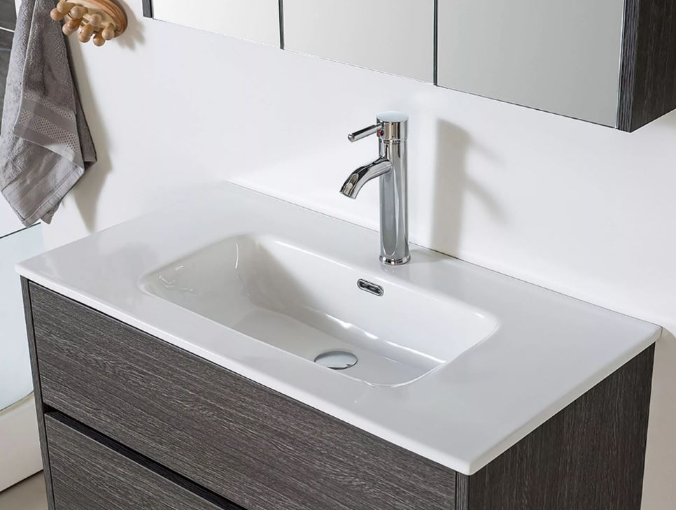 Moderne wastafel met witte keramische waskom en chromen mengkraan op een donkerhouten badkamermeubel.